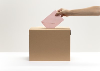 hand puts pink envelope into vote box